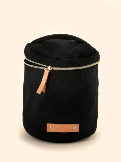 Sort toilettaske med THE INMANI plejeprodukter ved siden af